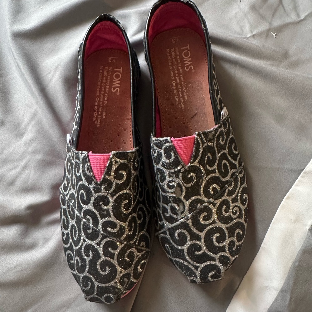 TOMS Black Glitter Swirl Slip-Ons with Pink Accent
